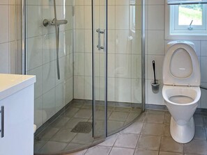 A bathroom with a glass-enclosed shower, a toilet, and a window. - 4 Star Holiday Home in Averoy (Averoy)