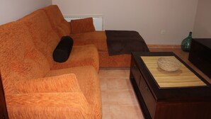 Ein Wohnzimmer mit einem orangefarbenen Sofa, einem dunkelbraunen Sofa und einem Couchtisch aus Holz mit einem gewebten Korb.