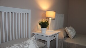 Ein Schlafzimmer mit Bett, Nachttisch, Lampe und einer Topfpflanze.