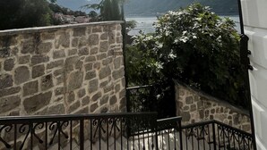 A stone wall, a metal railing, and a view of a lake with mountains in the background.