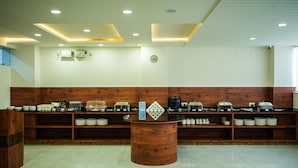 A buffet area with a central serving counter and multiple shelves of dishes. - Zip By Spree Hotels Purple Orchid Whitefield (Bengaluru)
