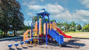 Une aire de jeux avec un toboggan, des structures d’escalade et un espace de jeux couvert.