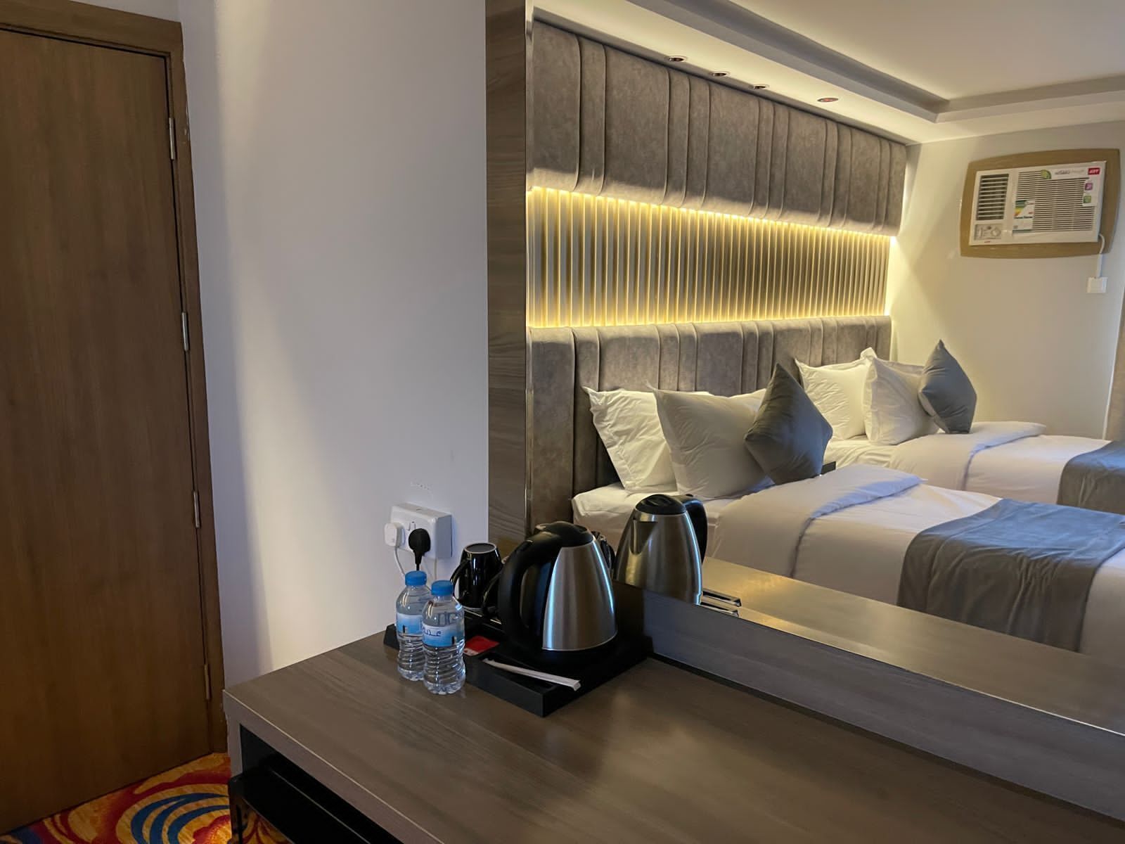Habitación de hotel con una cama grande, mesitas de noche, un espejo y un aire acondicionado de pared.