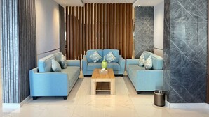 A modern living room with a sectional sofa, a wooden accent wall, and a marble accent wall. - Sweet Land Hotel (Umluj)