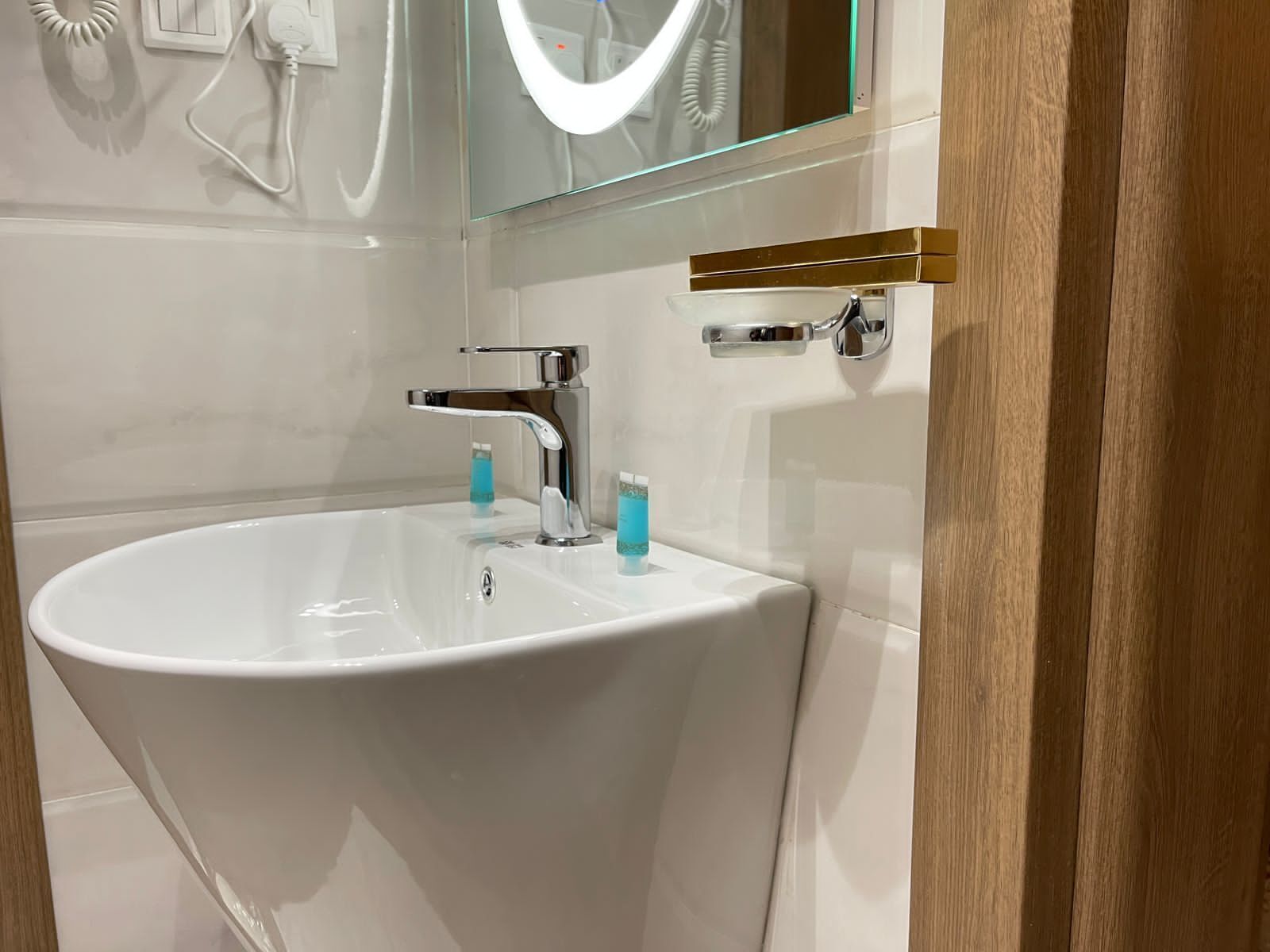 Un baño moderno con un lavamanos blanco, grifo cromado y espejo con recinto de vidrio.