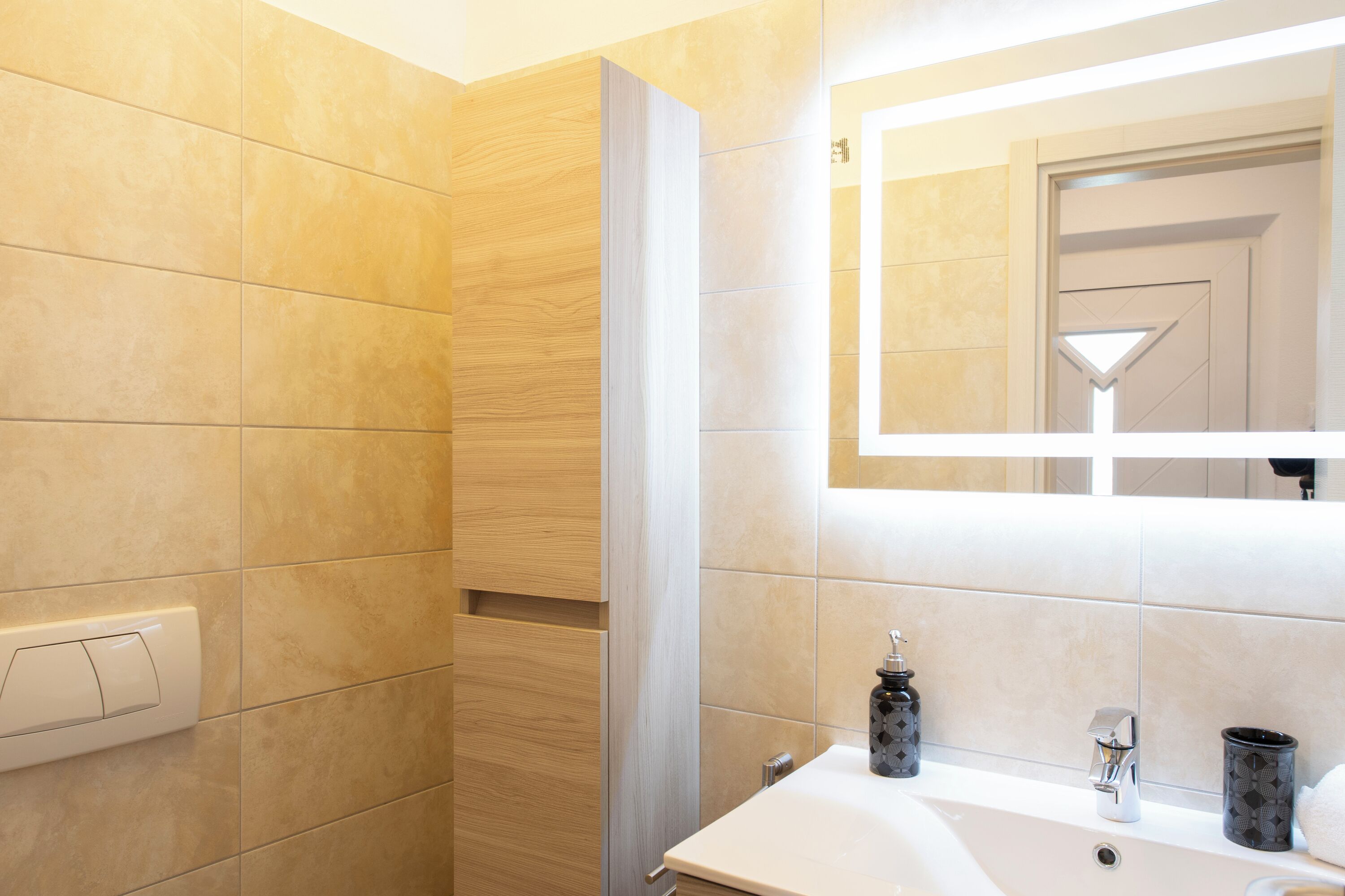 Un bagno con un lavandino bianco, uno specchio e uno spazio doccia.