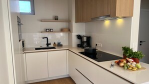 A modern kitchen with white cabinets, a black stove, and a wooden countertop. - Seashore (Koksijde)