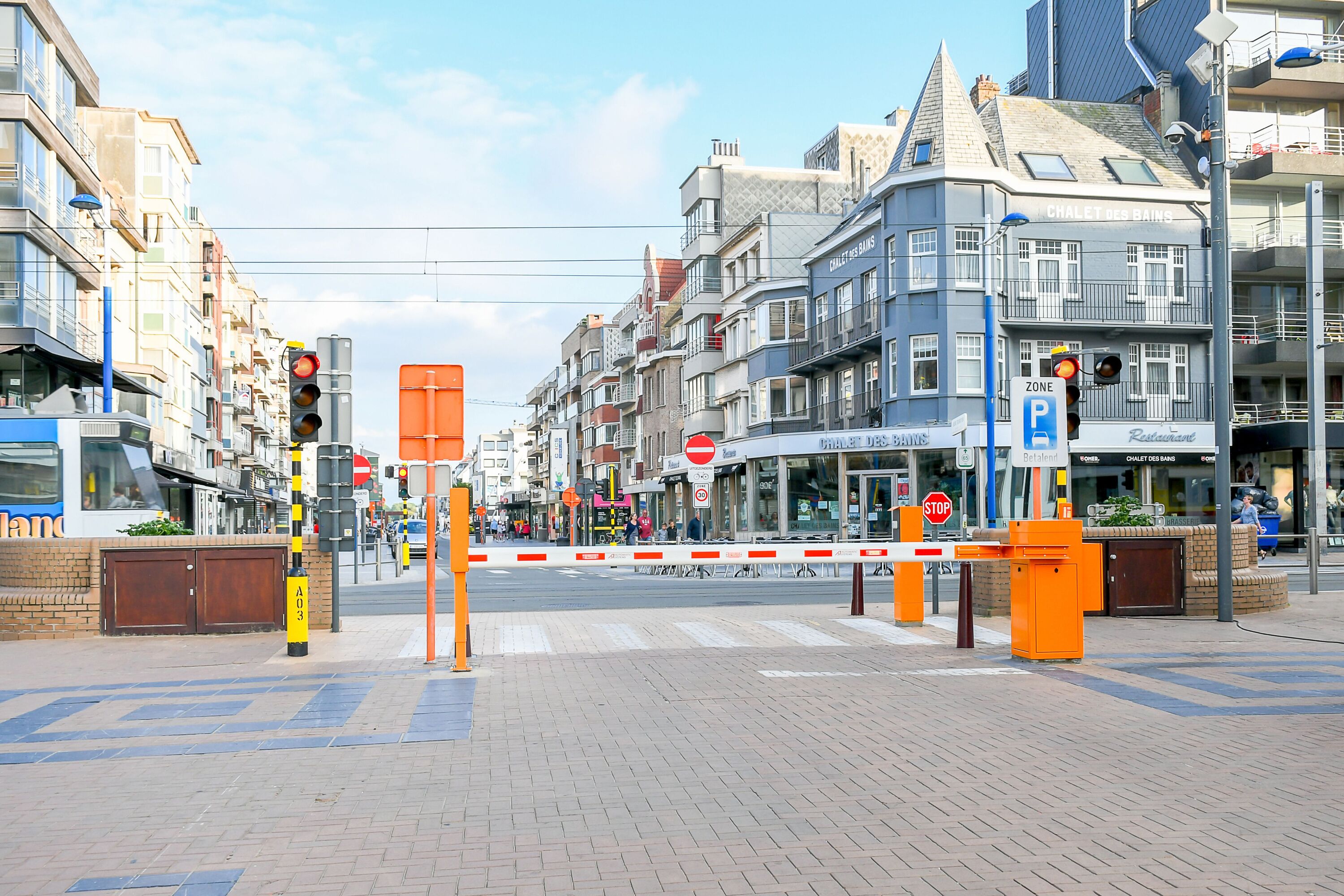 A street view with a gated entrance, buildings, and a restaurant sign.