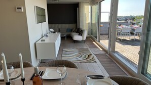 Un comedor moderno con vistas al exterior, un sofá y una mesa de comedor decorada con velas y copas.