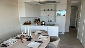 Una cocina moderna con muebles blancos, una isla central y un comedor con una mesa redonda para cuatro personas.