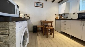 A compact kitchen with a washing machine, a dining table with chairs, and a microwave. - 3-room apartment for 4 in Châtelaillon-Plage with parking (Châtelaillon-Plage)