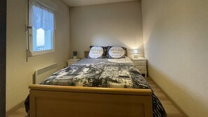 A bedroom with a bed, two bedside tables, a nightstand, a window with curtains, and a hanging light fixture. - 3-room apartment for 4 in Châtelaillon-Plage with parking (Châtelaillon-Plage)