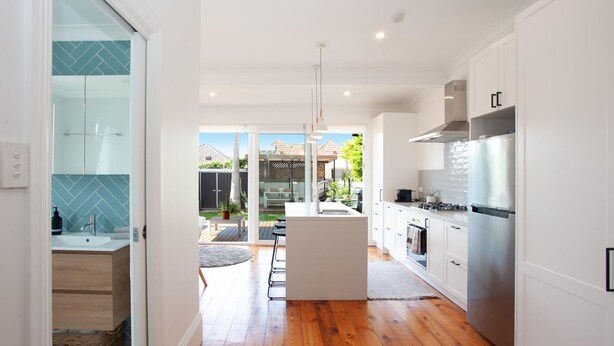 A modern kitchen with a central island, stainless steel appliances, and a view to a backyard patio.