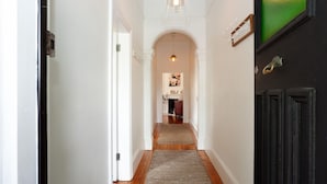 A hallway with a wooden floor, white walls, and a black door on the right.