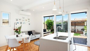 A modern kitchen with a central island, a dining area with a white table and chairs, and a cozy seating area with a sofa.