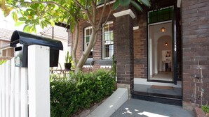 A brick building with a large window, a mailbox, and a tree in front.