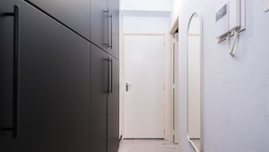 A hallway with a door at the end, a telephone on the wall, and a mirror. - Westend Palace (Middelkerke)