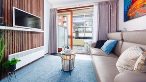 A modern living room with a sofa, a coffee table, a TV, and a potted plant. - Westend Palace (Middelkerke)