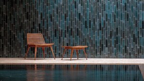 Un área de piscina con dos sillas de madera y una pared con azulejos.