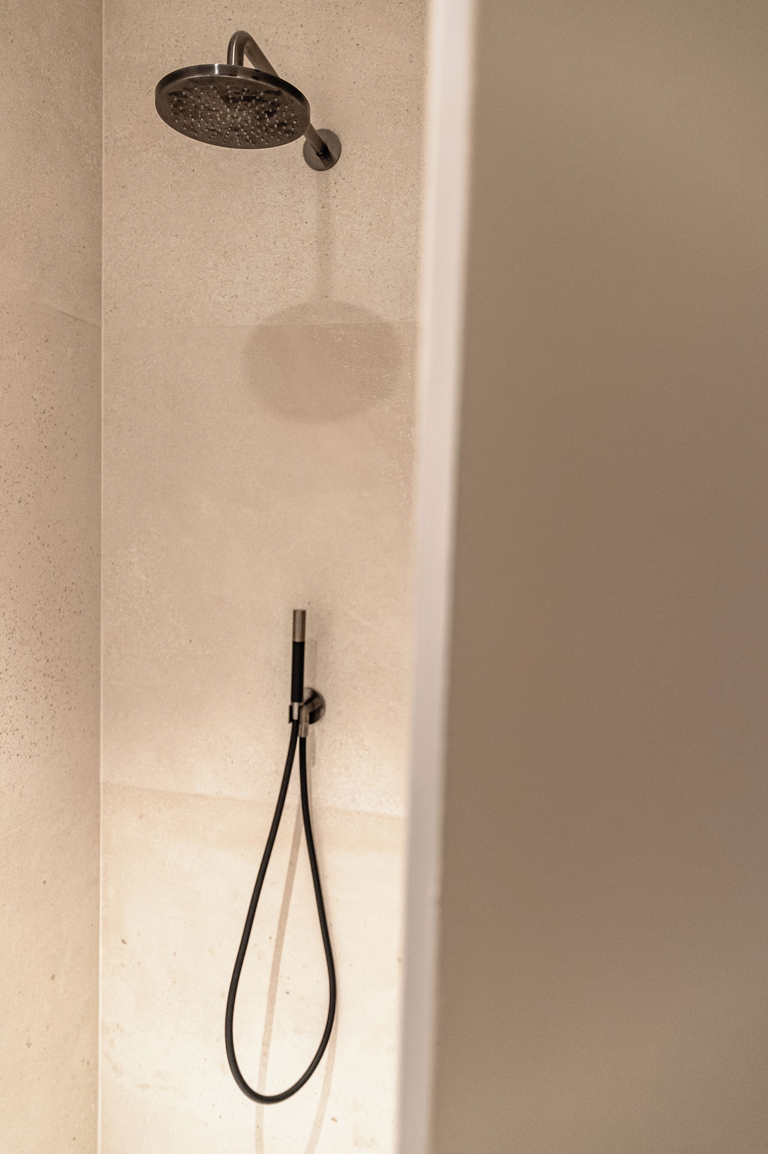 A shower with a handheld showerhead and a fixed showerhead.