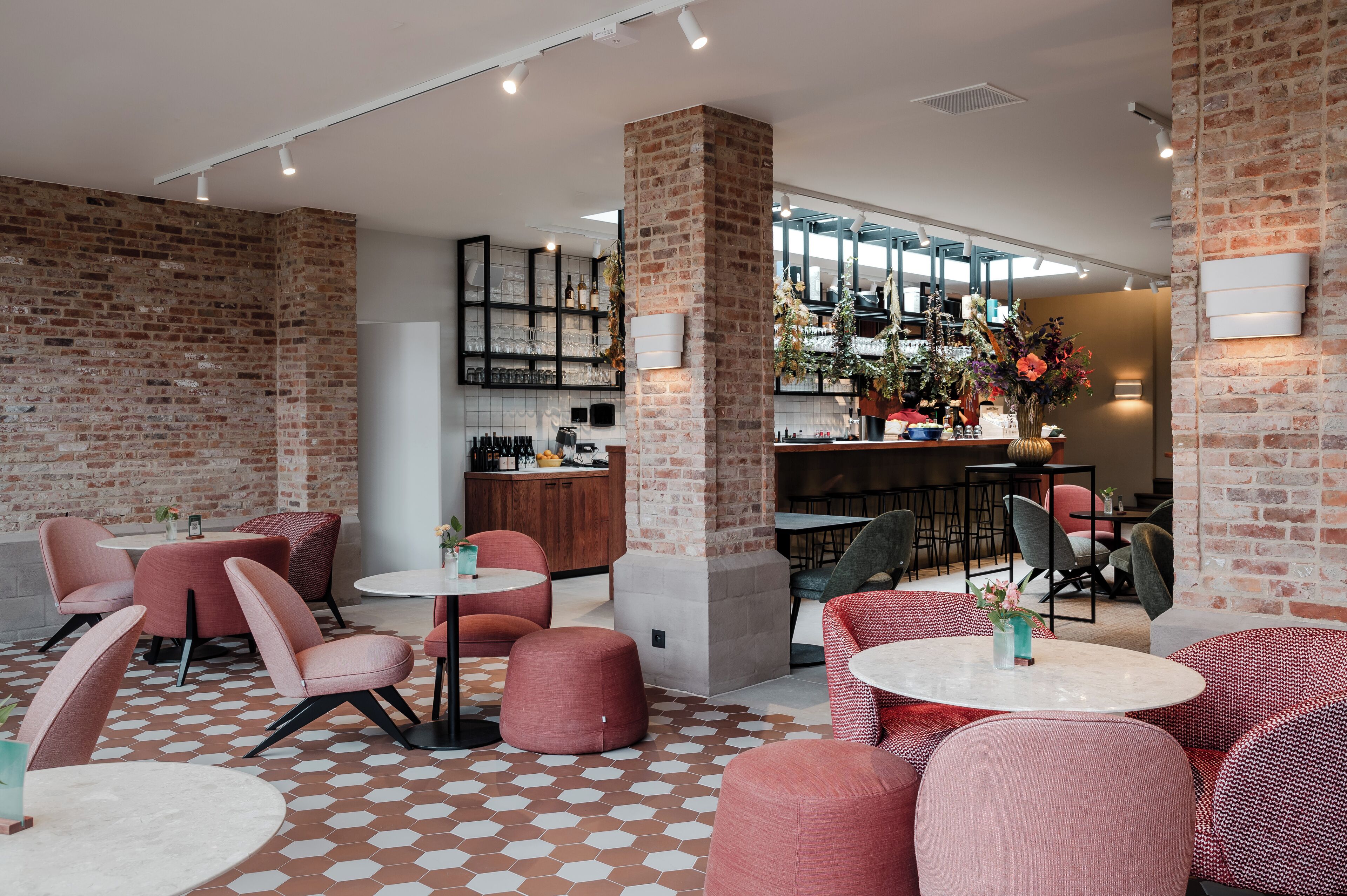 A modern lounge area with brick walls, round tables, and comfortable seating.