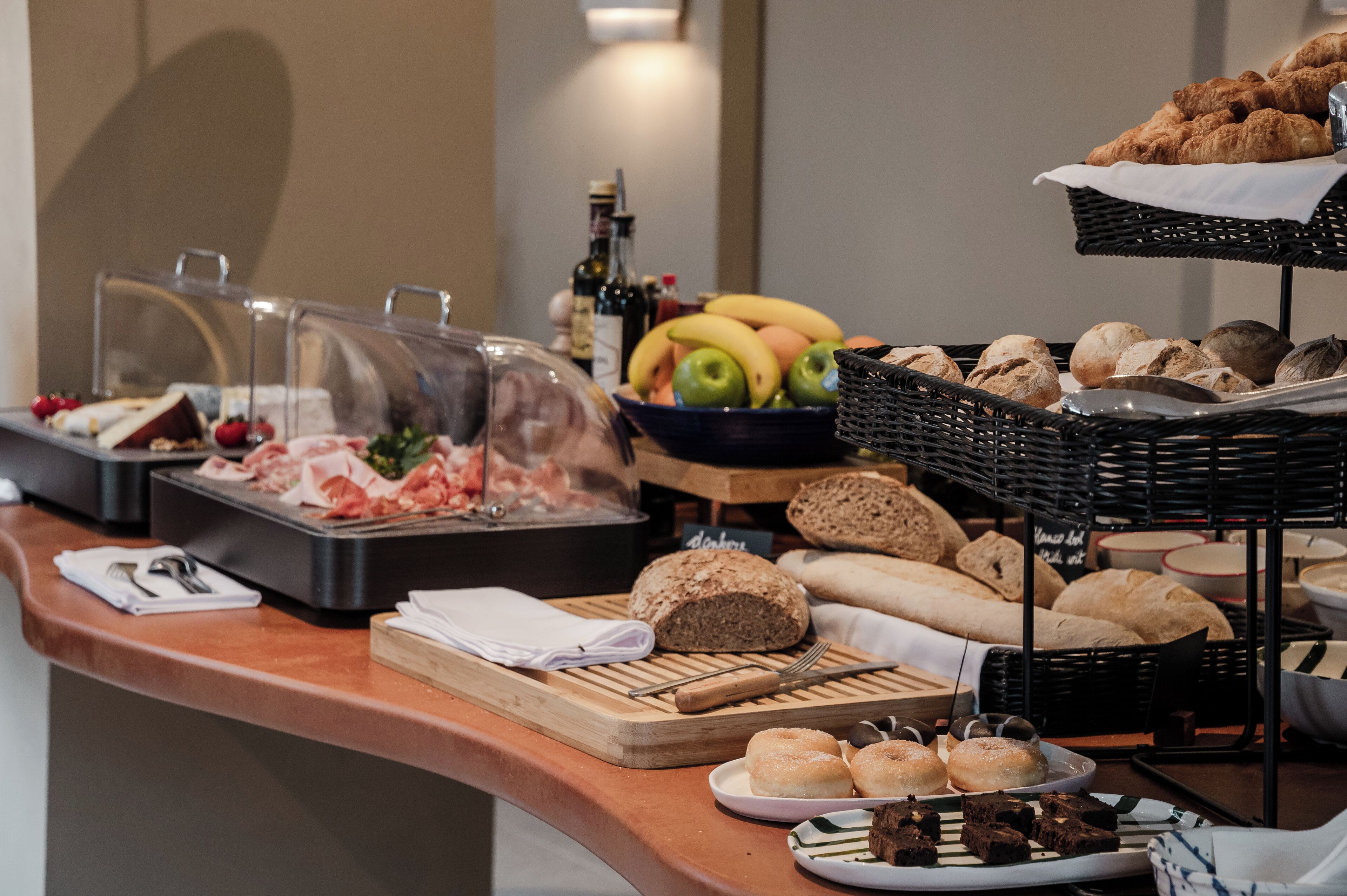 A buffet with various food items including bread, pastries, and fruits.