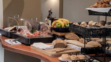 A buffet with various food items including bread, pastries, and fruits.