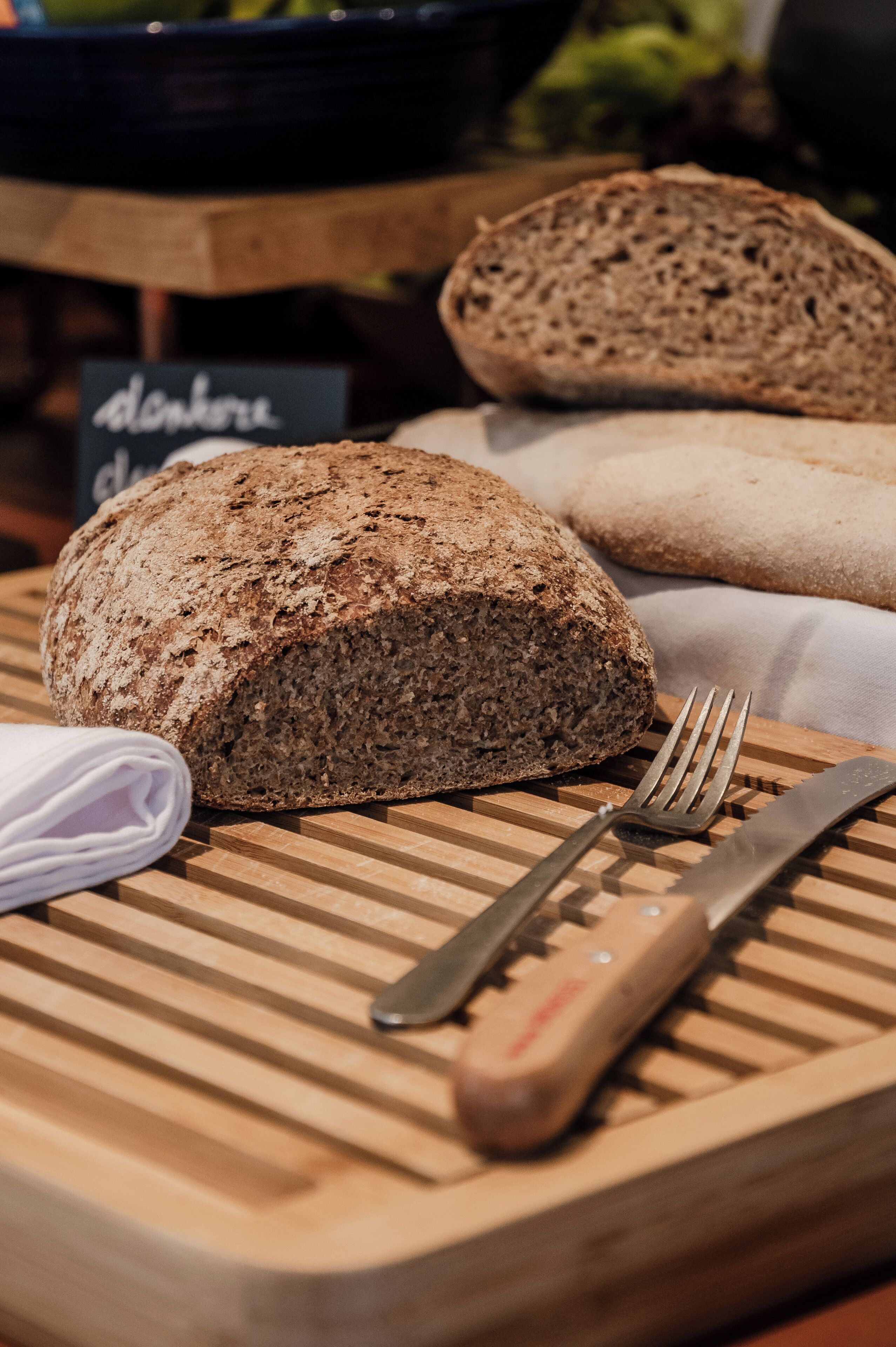 Ein Brot auf einem Holzschnittbrett mit Messer und Gabel daneben.