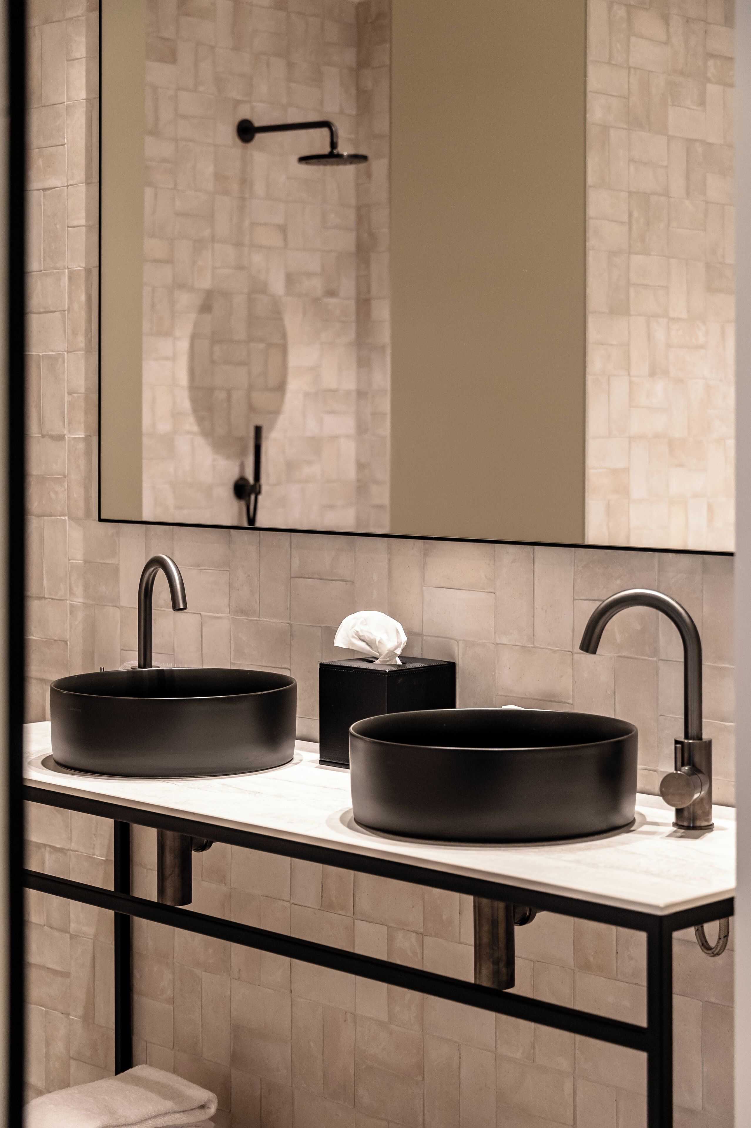 A modern bathroom with two black sinks, a mirror, and a towel rack.