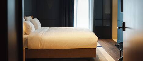 Un dormitorio moderno con una cama grande, paredes oscuras y suelo de madera.