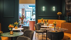 Un interior de restaurante con mesas redondas, asientos acolchados y centros de mesa florales.