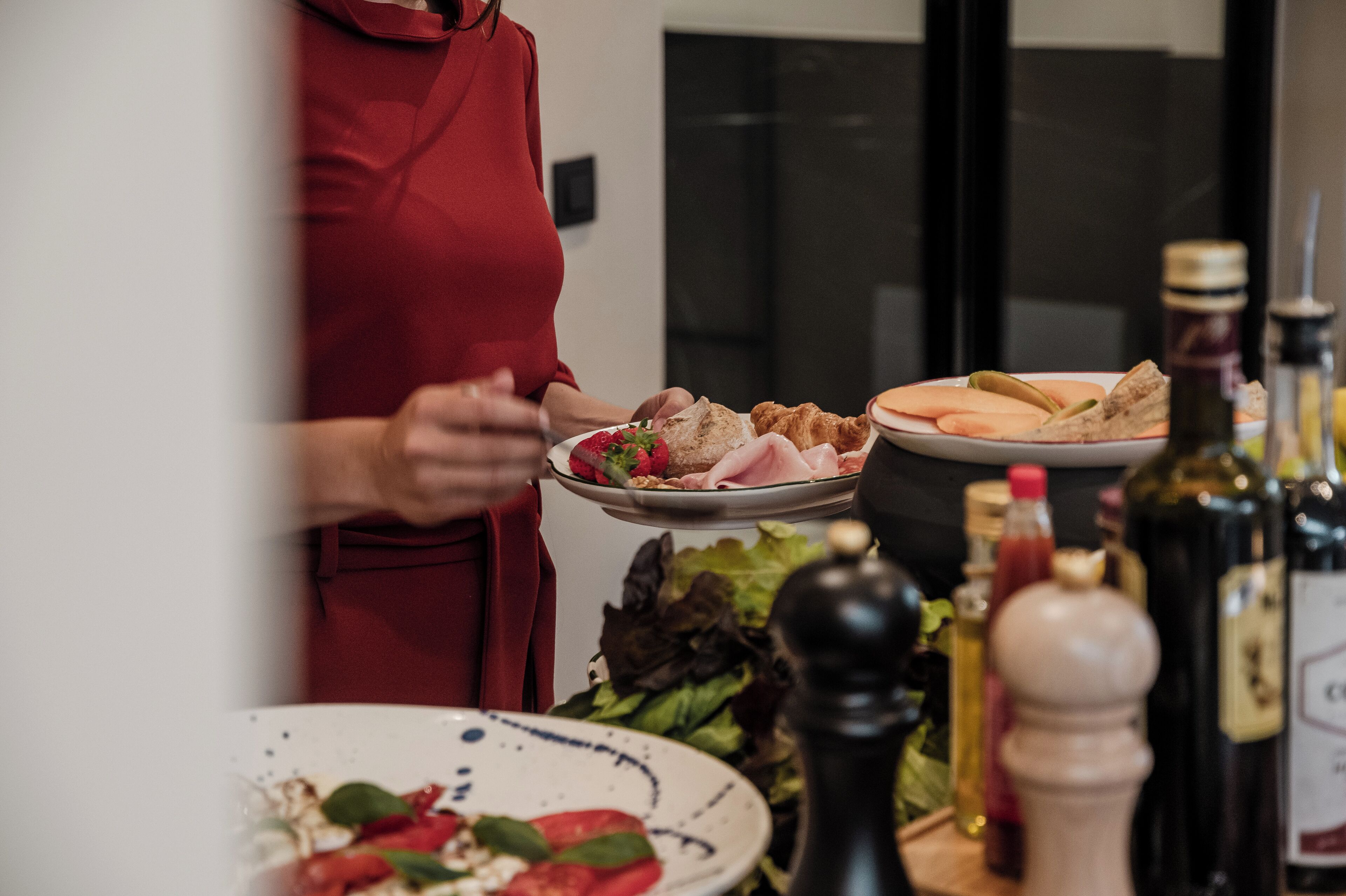 A person serving food on a plate with various condiments and a salad visible in the foreground.