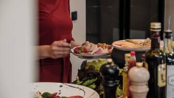 A person serving food on a plate with various condiments and a salad visible in the foreground.