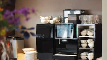 A coffee station with a coffee machine, dispensers, and a variety of cups and saucers.