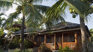 Ein tropisches Resort mit einem strohgedeckten Gebäude, Stein-Pflanzgefäßen und üppiger Vegetation.