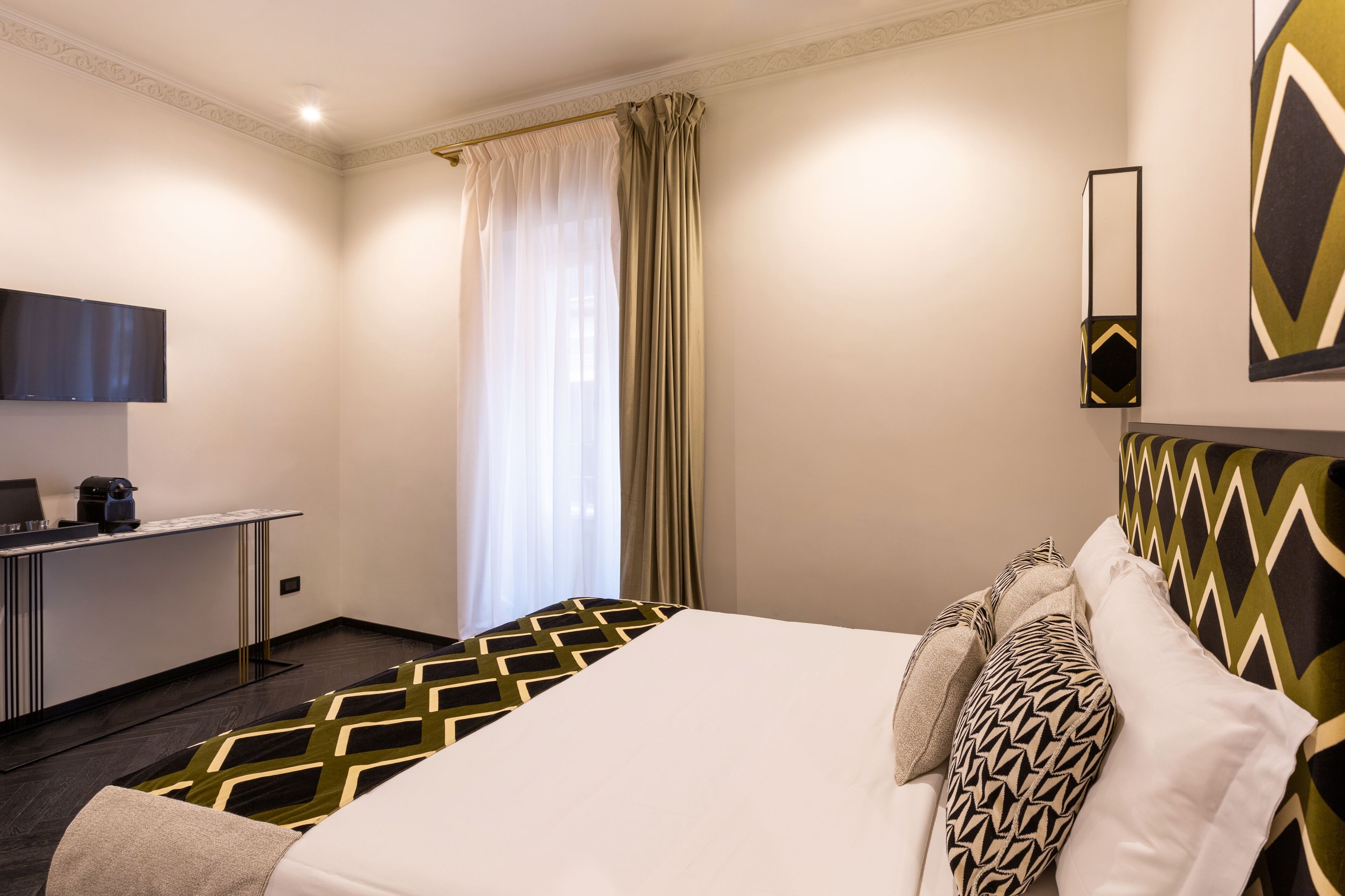 A hotel room with a bed, a desk, and a television.