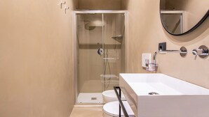 A modern bathroom with a glass-enclosed shower, a white sink, and a large mirror. - The Couper Colonna (Rome)