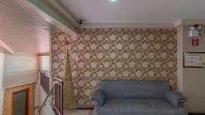 A living room with a grey sofa, a decorative tree, patterned wallpaper, and a staircase. - OYO 767 Hotel Urban - Khotel Kurban Hotel (Baguio)