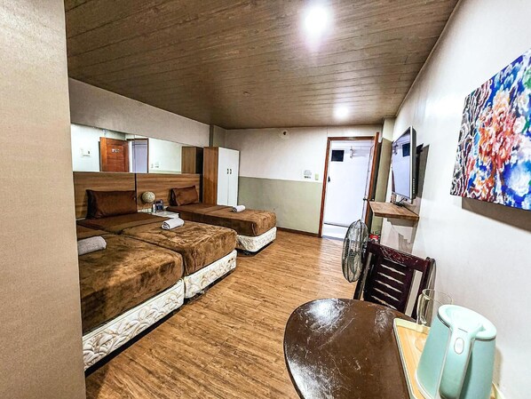 Quarto de hotel com duas camas, teto de madeira, televisão e um quadro colorido na parede.