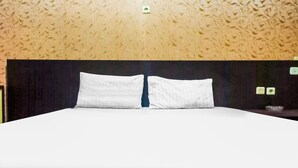 A neatly made bed with white linens and two pillows, a dark headboard, and a patterned wallpaper. - Hotel O Lima Dara (Tanjung Selor)