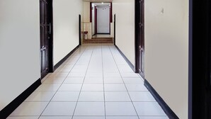 A corridor with white tiled floors and dark trim, leading to a door at the end. - Hotel O Lima Dara (Tanjung Selor)
