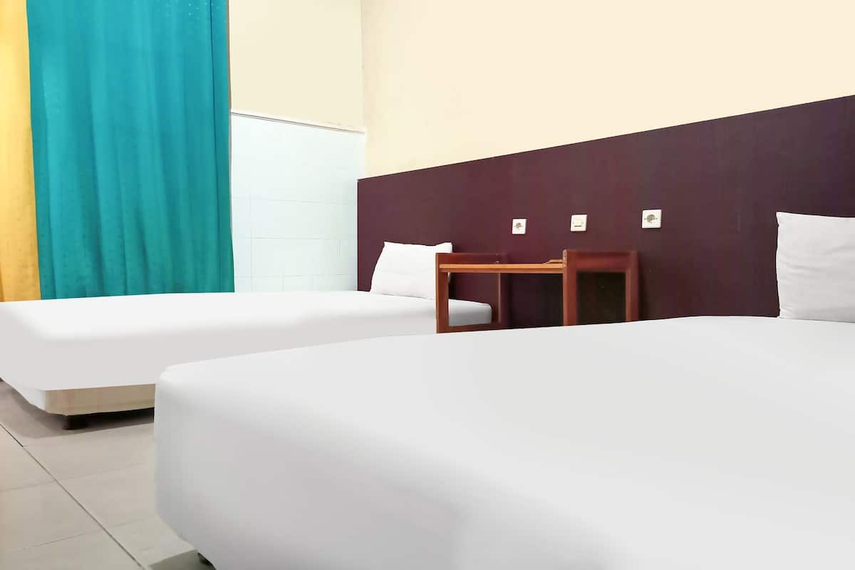 Ein Hotelzimmer mit zwei Einzelbetten, einem Holznachttisch, einem weißen Stuhl und einem blaustürkisen Vorhang.