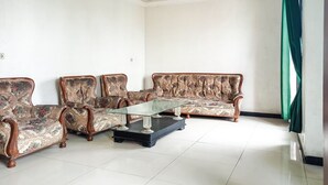 A living room with a sofa, two armchairs, and a glass coffee table. - Hotel O Lima Dara (Tanjung Selor)