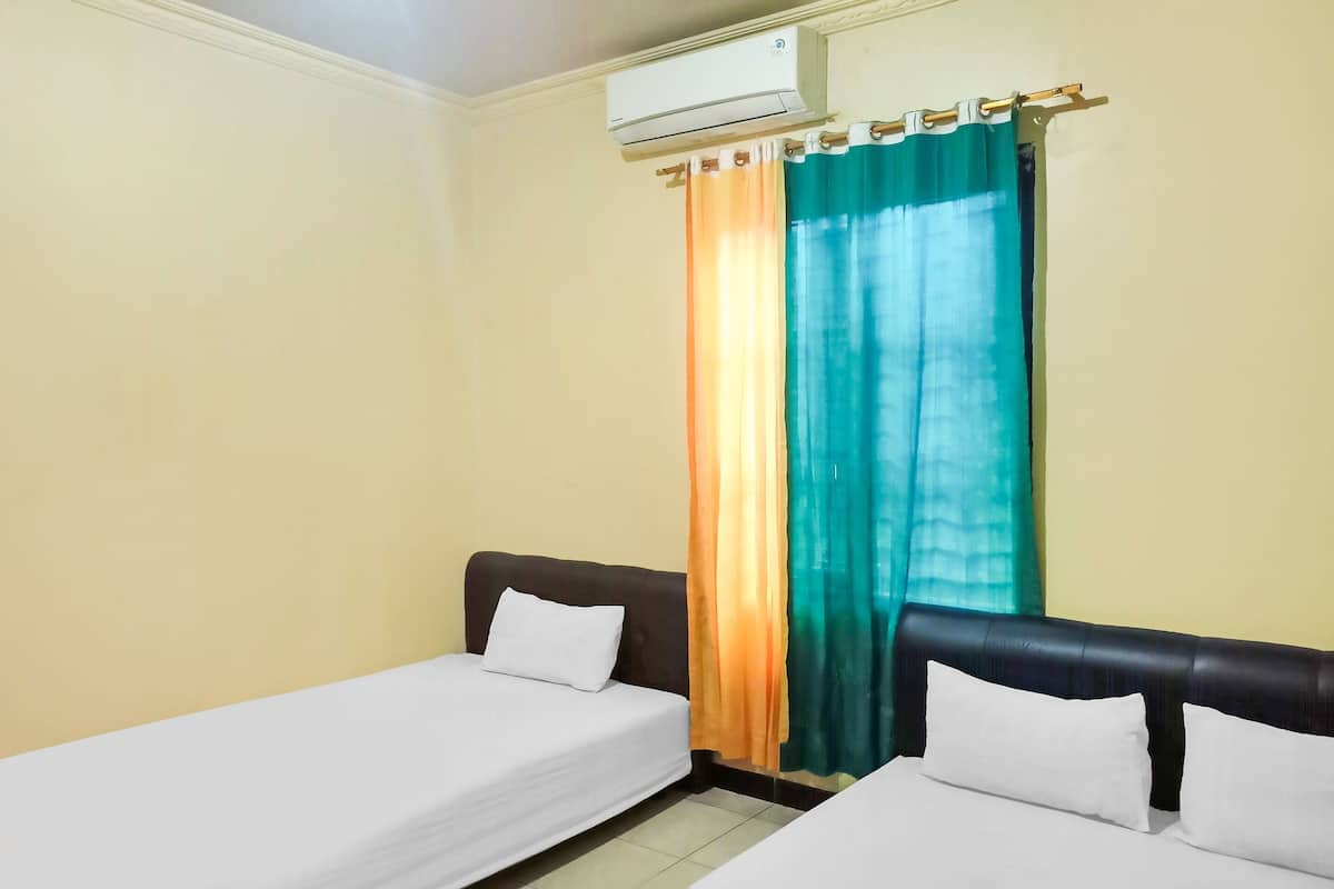 Ein Hotelzimmer mit zwei Einzelbetten, einem Fenster mit Vorhang und einer Klimaanlage.