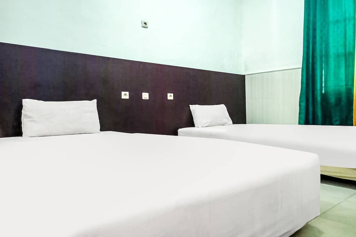 Ein Hotelzimmer mit zwei Einzelbetten, einem dunklen Kopfteil und einem grünen Vorhang.
