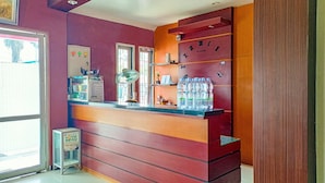 A reception area with a counter, a clock, and a security camera. - Hotel O Lima Dara (Tanjung Selor)