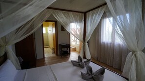 A bedroom with a bed, white curtains, and a view of a hallway. - Bellevue Tamarin (Tamarin)