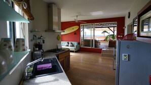 A kitchen with a wooden countertop, a sink, and a stove. There is a ceiling fan and a surfboard on the wall. - Bellevue Tamarin (Tamarin)