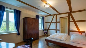 A bedroom with a wooden bed, a wooden wardrobe, a chair, a desk, and a window with curtains. - Large vacation apartment in an old pastorate with fireplace and garden (Borrentin)