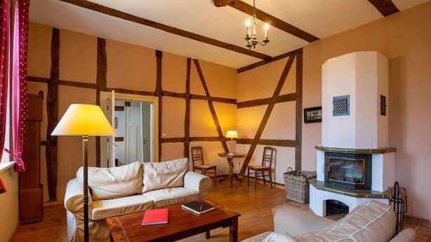 A cozy living room with a fireplace, a sofa, a coffee table, and two lamps. - Large vacation apartment in an old pastorate with fireplace and garden (Borrentin)